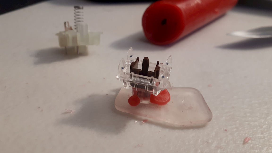 An opened switch with a keycap and wax pouring out the stem.