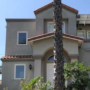 light grey stucco home with a dark brown ceramic roof
