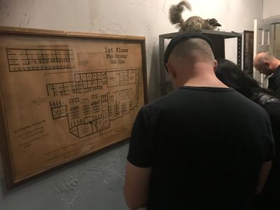 Multiple people in a locked room with a building map on the wall