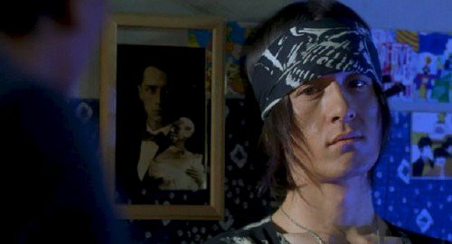A close-up screenshot of Jia Hongsheng wearing a patterned bandana playing as himself. From the film 'Quitting'.