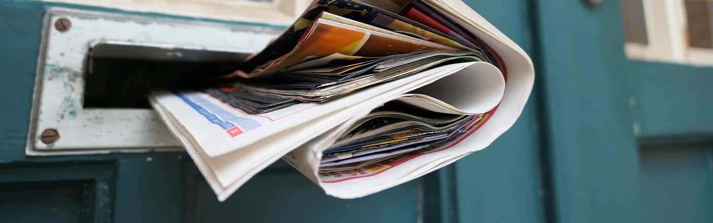Neuigkeiten Zeitung die aus Zeitungsschlitz bei blauer Holztuer guckt