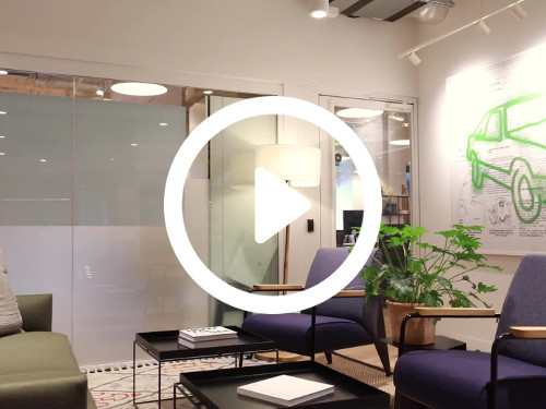 Well lit personal meeting space containing shielded windows next to wall art of car and basic office seating Skype background