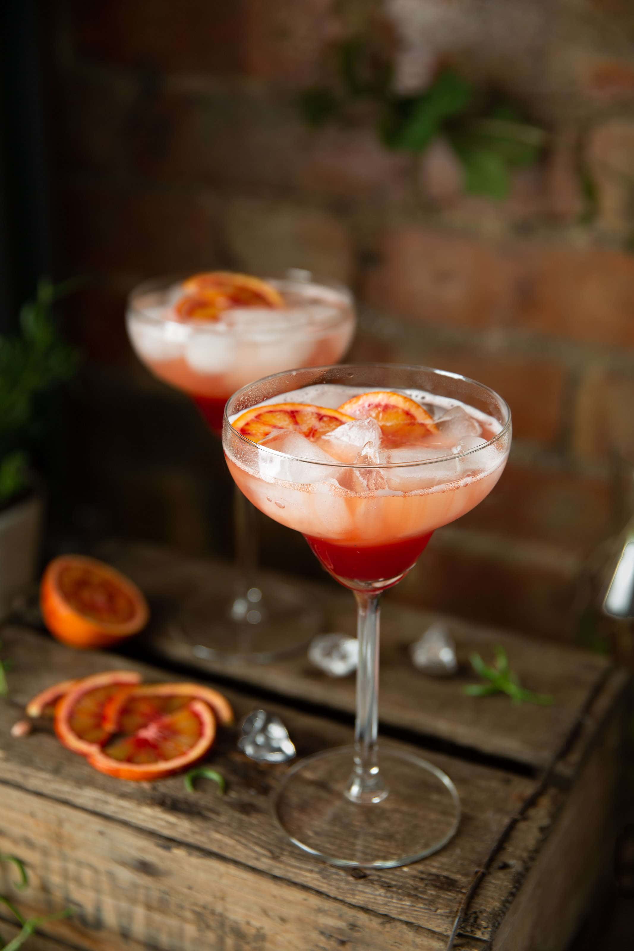 blood orange cocktail in margarita glasses placed on a wooden box.