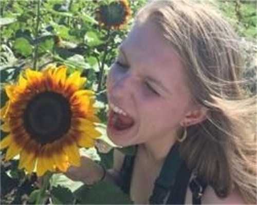 Christina pretending to eat a sunflower.