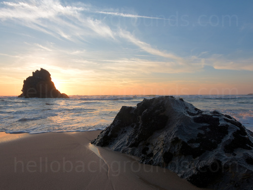 Sandy beach with rocky outcrop and foaming gentle waves Skype background