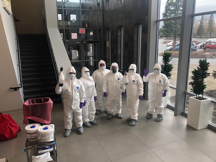 group of cleaning professionals dressed in protective suits and masks.