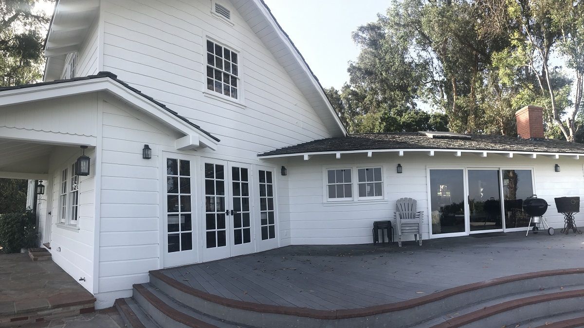 enlarged photo of white painted home exterior with dark painted deck