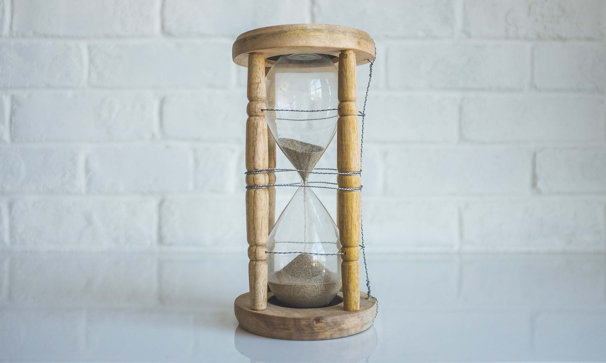 Hourglass sitting on white marble counter with time running out