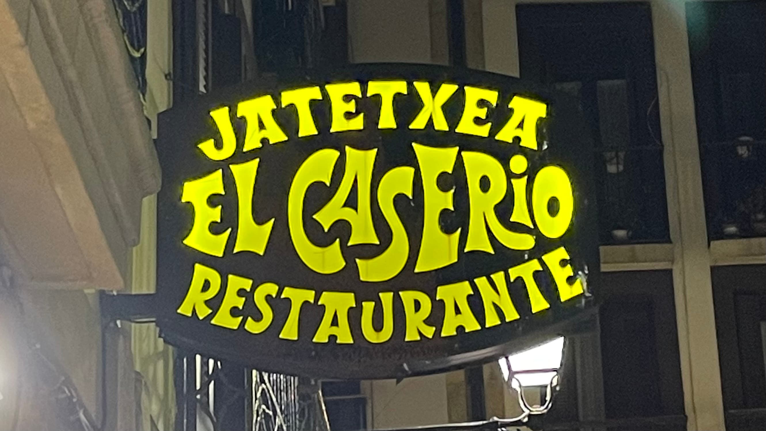 A restaurant sign written in Basque with large, bold yellow letters on a black background.