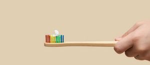A toothbrush with rainbow-coloured bristles and a dab of toothpaste on it