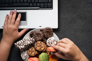 Unhealthy snack at work time. Compulsive indulgence, overeating, stress, high calorie, fattening junk food, weight gain. Woman eating cookies at workplace vagina health