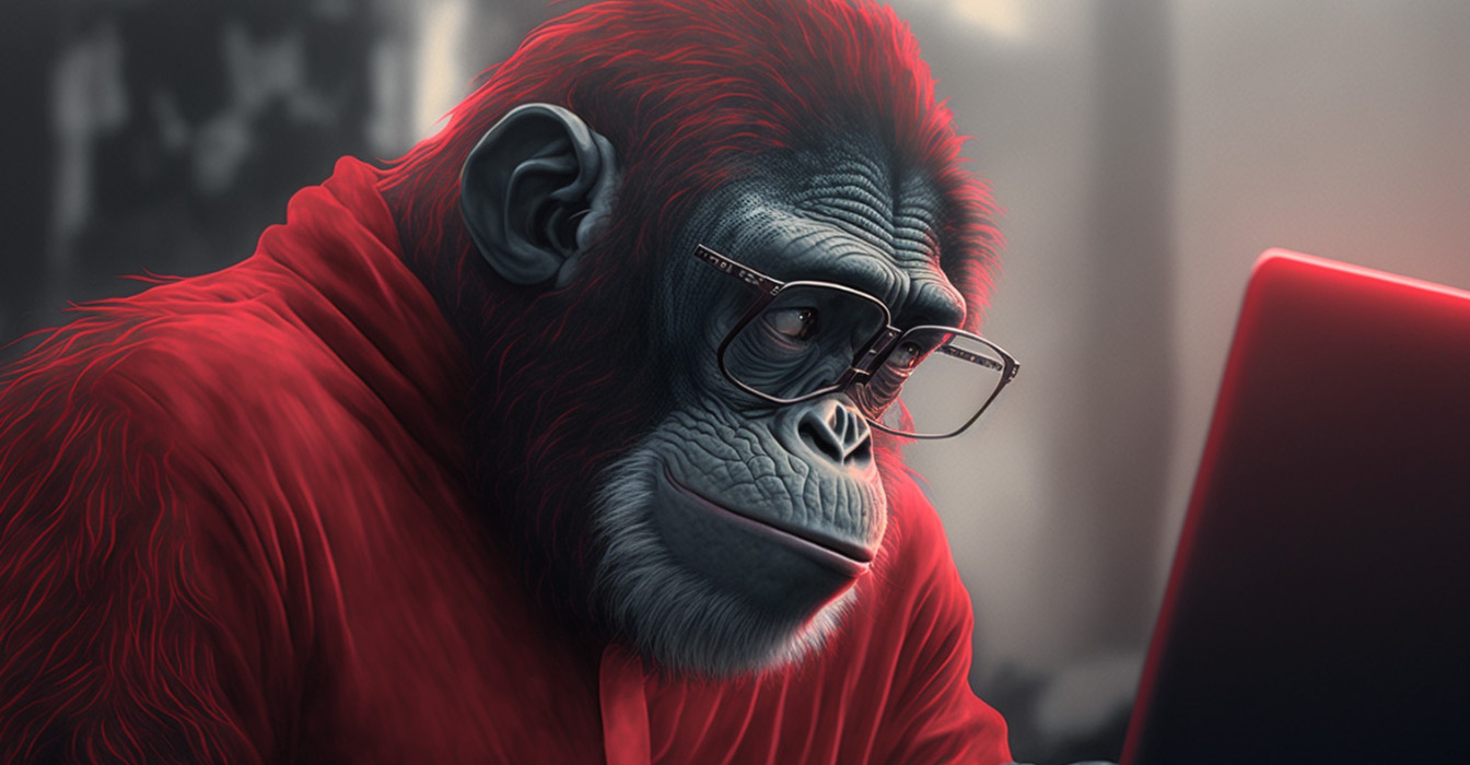 Ape wearing a red shirt glancing over its laptop screen