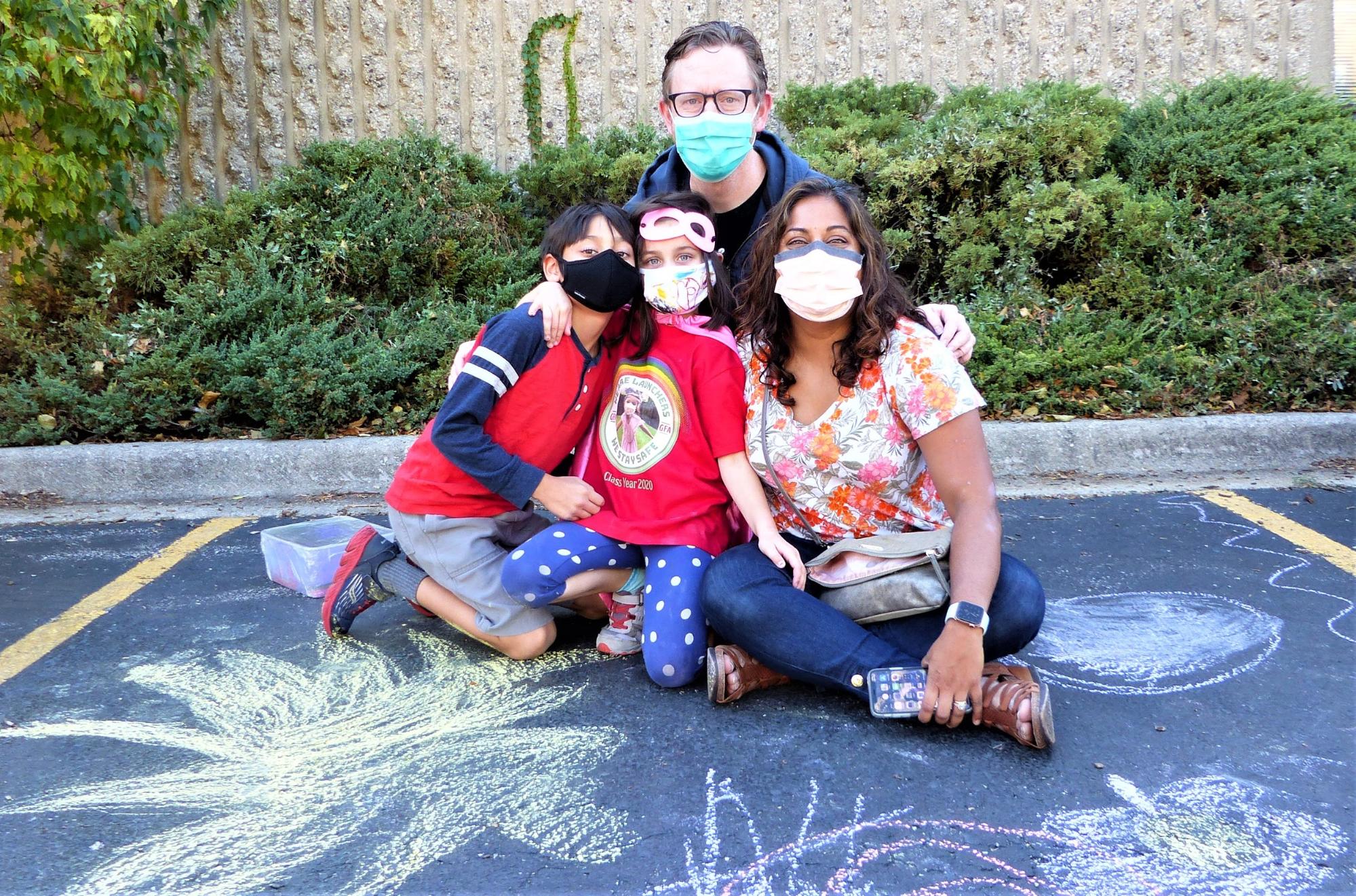Four community members outside with chalk art.