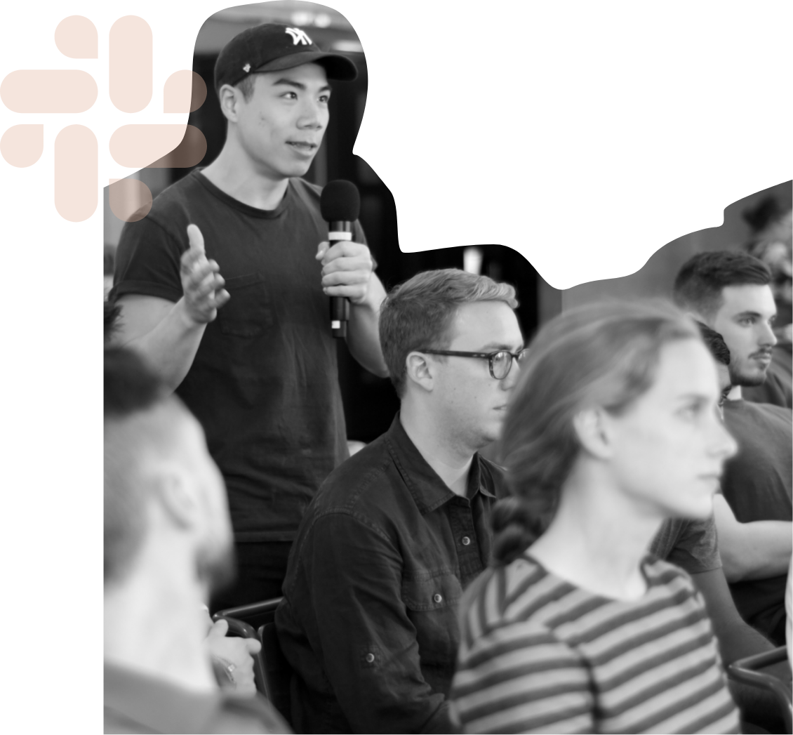 black and white photo of man holding microphone and speaking in a seated crowd