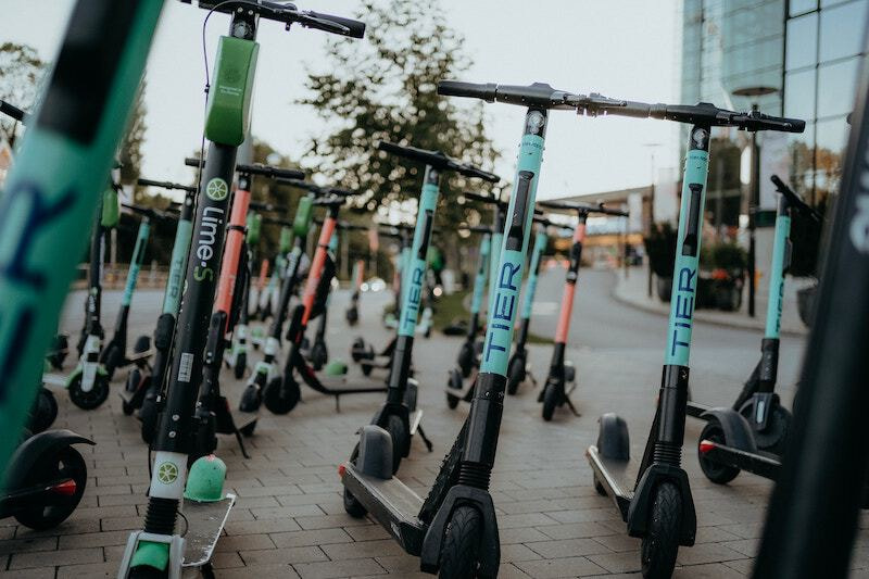 Multiple tier, lime and voi kick-scooters standing tilted on the street.