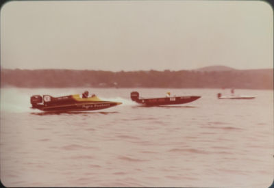 Two speedboats race across the waters at Punggol. A shoreline of dense trees is pictured in the background.