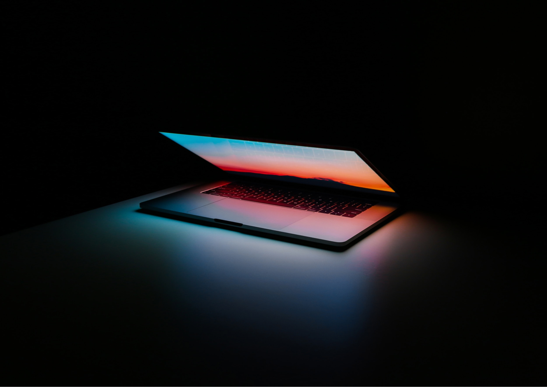 semi closed laptop in the dark reflecting its inner light