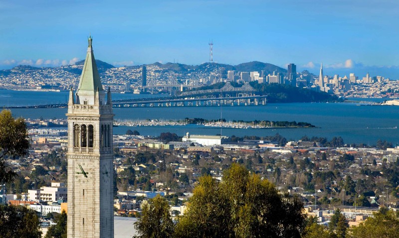 Sather Tower rises above UC Berkeley with San Francisco an the bay bridge in the background