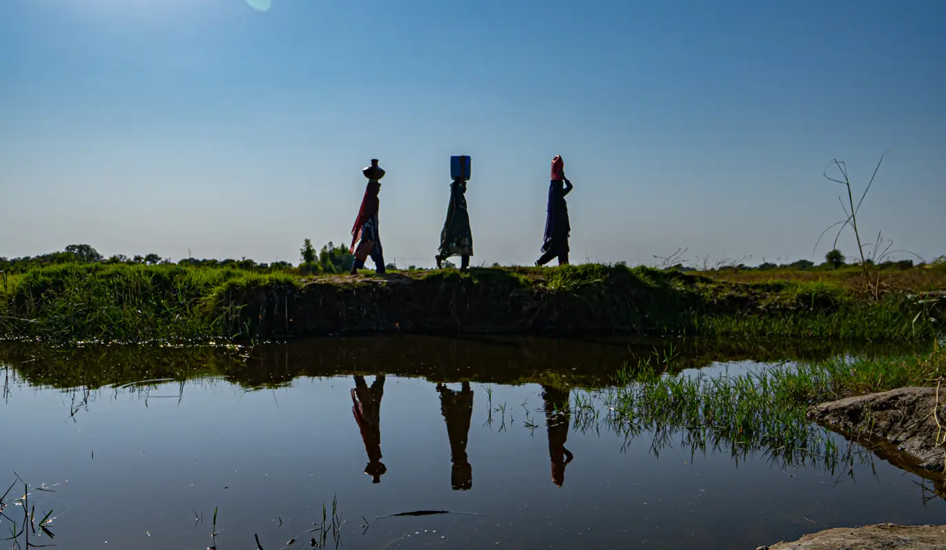 Women of the flood-affected community in Bangladesh on their way home carrying drinking water on their heads.