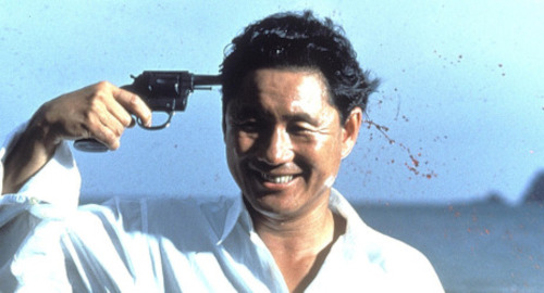 A screenshot of a yakuza man Murakawa (played by Takeshi Kitano), happily shooting himself in the head. From the film 'Sonatine'.