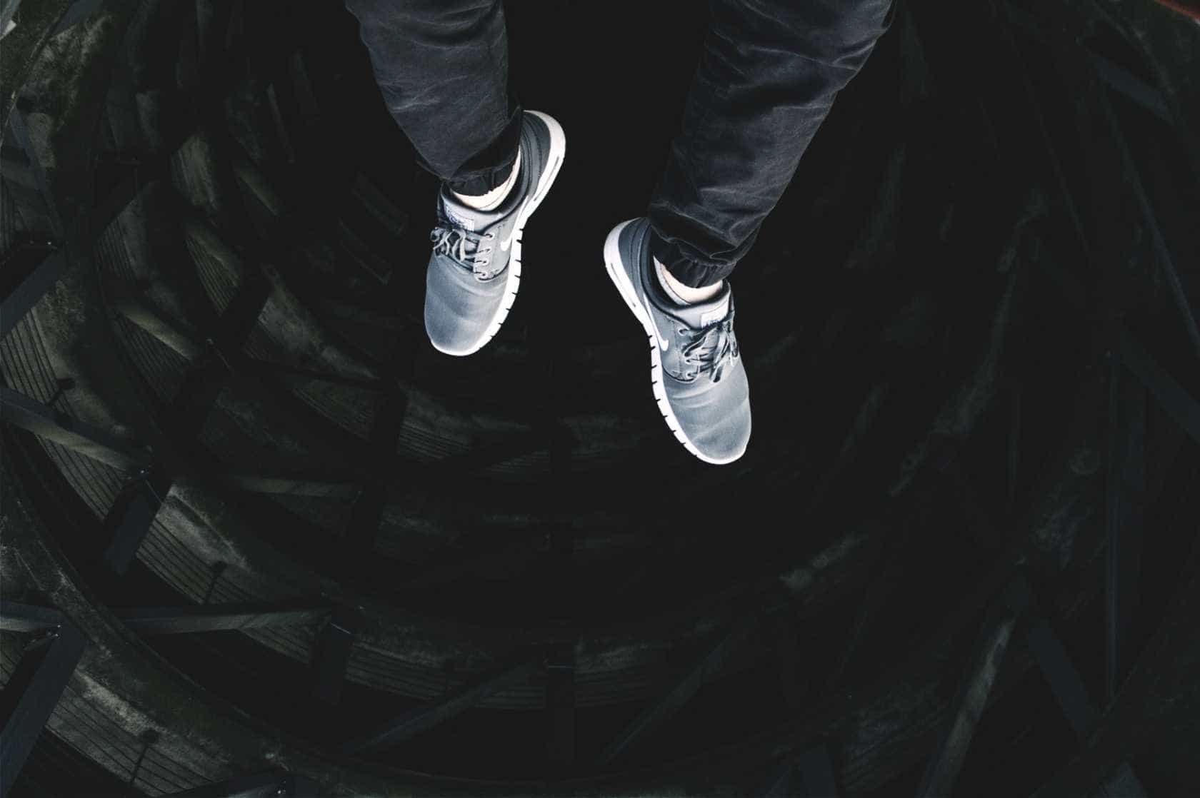 A man's feet, looking down from the top of a building