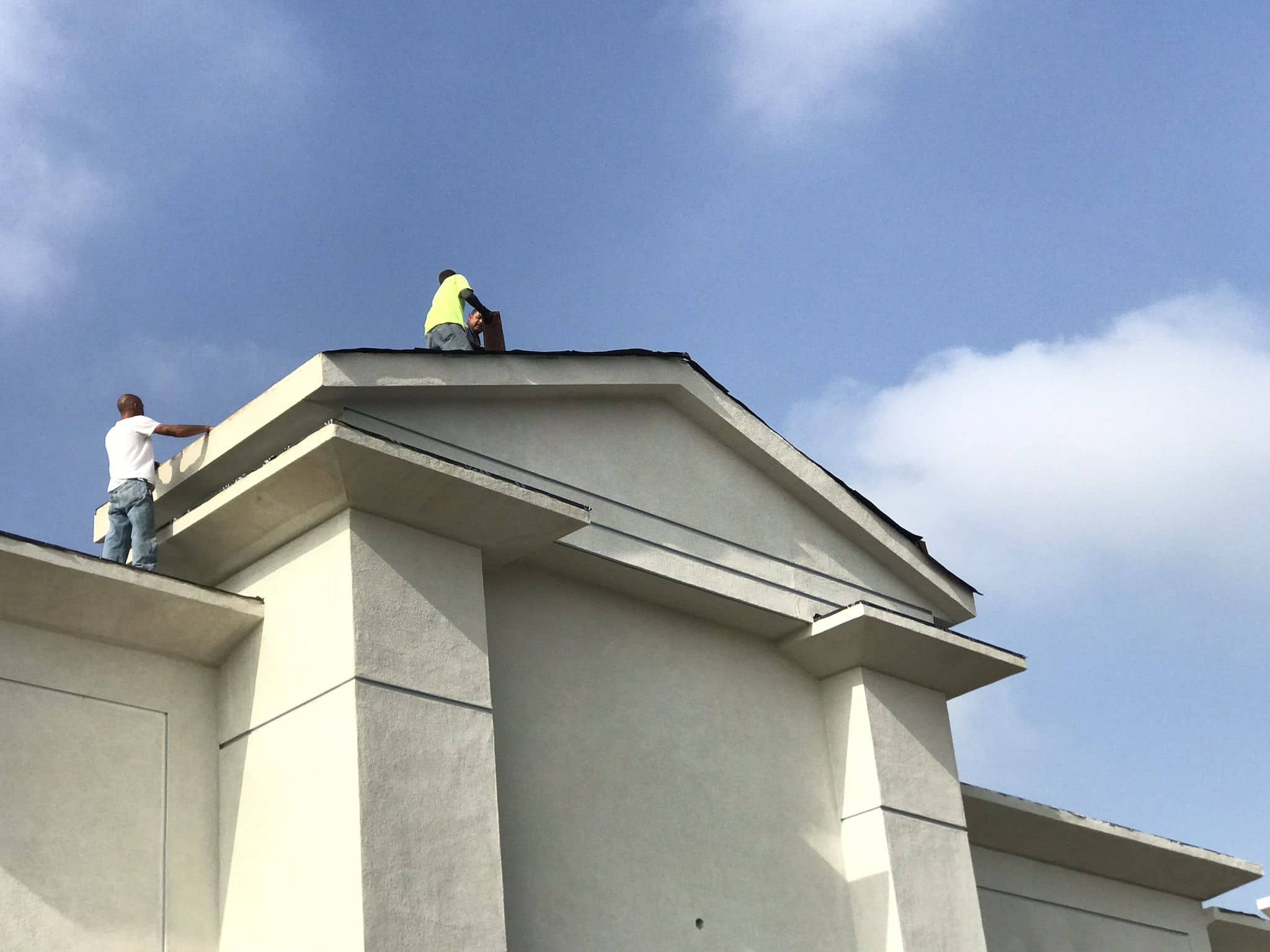 enlarged photo of man on top of a commercial building roof being painted