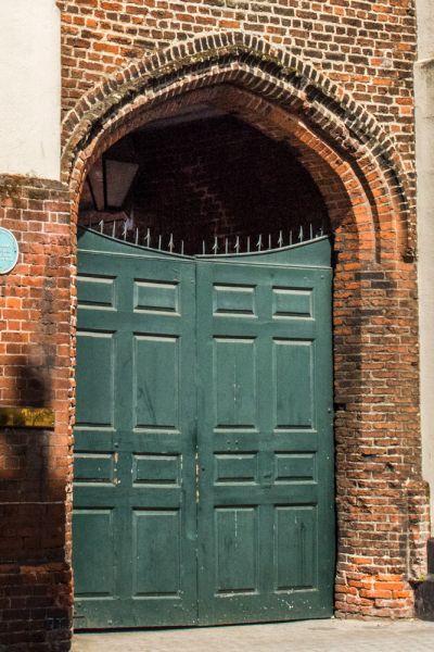 A green wooden gate under a stone arch