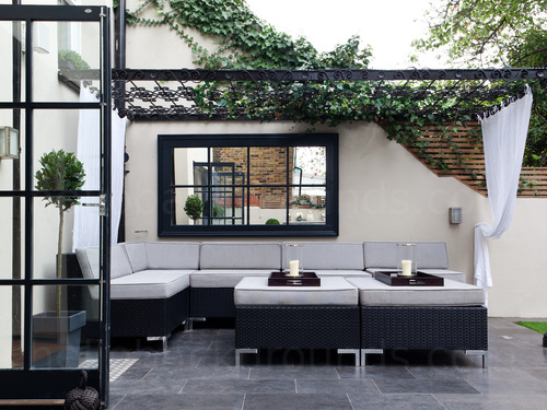 Contemporary garden lounge area decorated in black and white featuring a large corner sofa and overhead trellis Zoom background