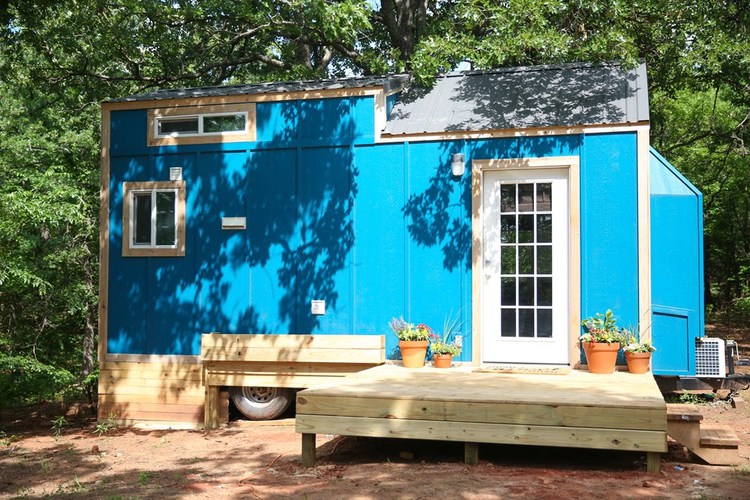Outdoor photo showing the blue tiny amenities building, with outdoor deck and a couple of windows. Outdoor photo showing the blue tiny amenities building, with outdoor deck and a couple of windows.
