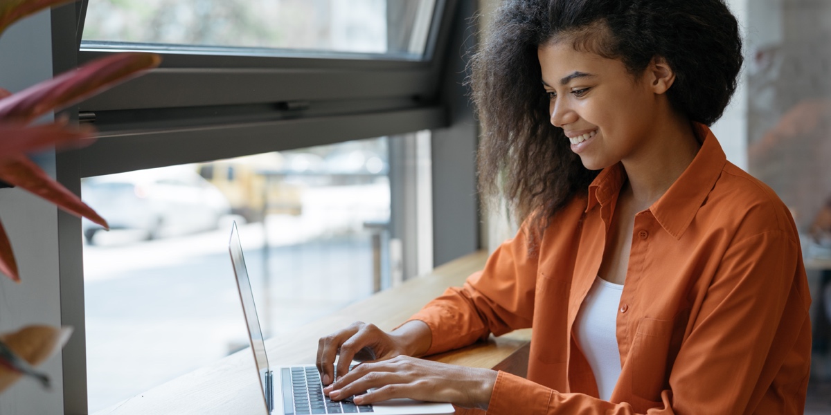 What Are the Best UX Job Boards? An aspiring UX designer sitting at a laptop near a window exploring UX job boards.