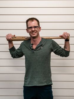 Matthew Hebert posing with a baseball bat and smiling.