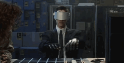 A scene from the film Johnny Mnemonic (1995), in which data courier Johnny (played by Keanu Reeves) hides a secret stash of information implanted into his mind. Here, the main character accesses the Net (a virtual-reality equivalent of the Internet) using special eyewear and gloves which allow him to navigate a virtual cityscape by gesturing with his hands.