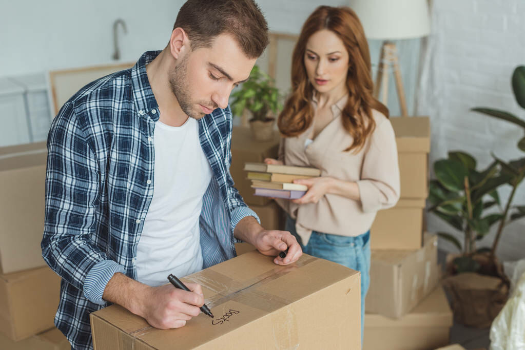 man signing cardboard box with wife