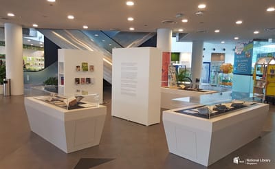 A photo of the roving exhibition. An information wall in the middle is surrounded by showcases and a wall with books.