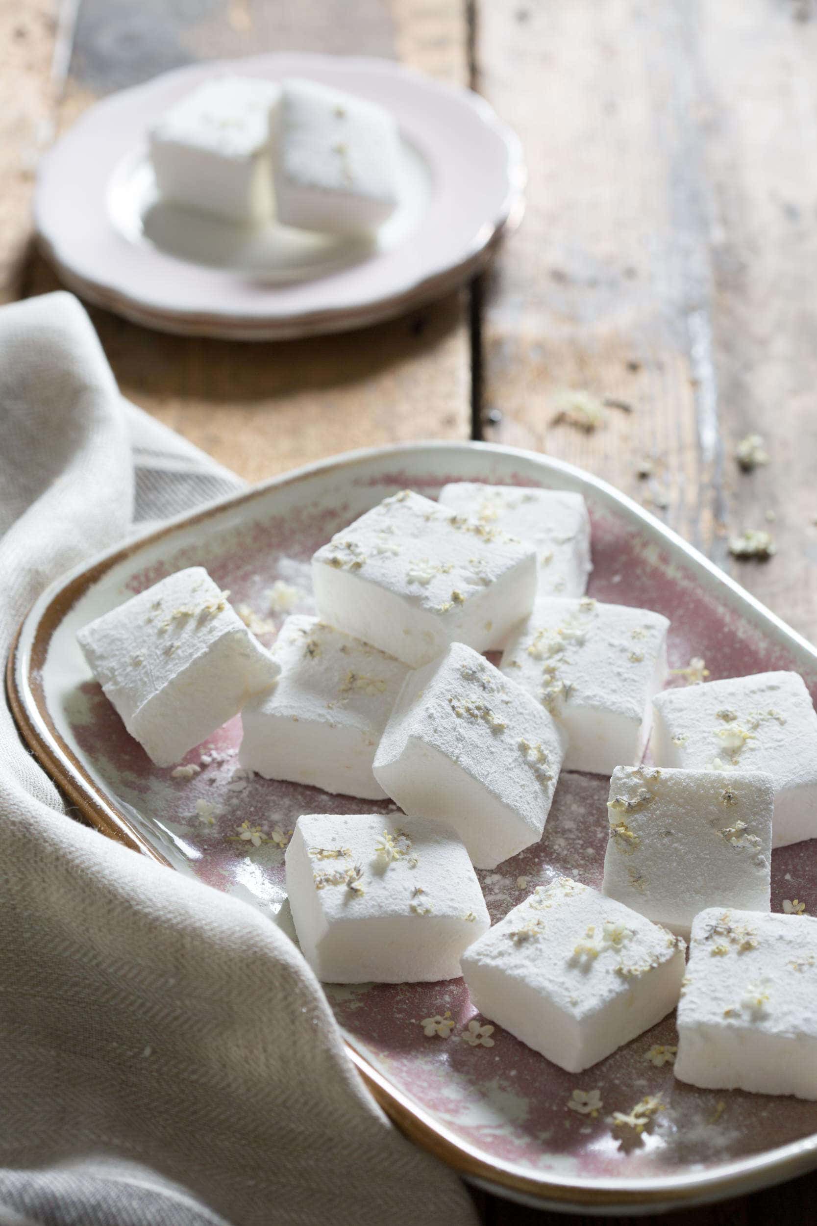 Elderflower and Lemon marshmallows on a pink plate sat on a linen crumpled cloth.