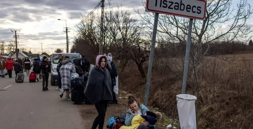 People wait with their belongings as they flee Ukraine for Hungary