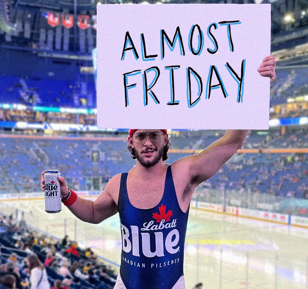 man in Labatt Blue leotard and a hockey game holding a labatt blue light and a sign that reads ALMOST FRIDAY