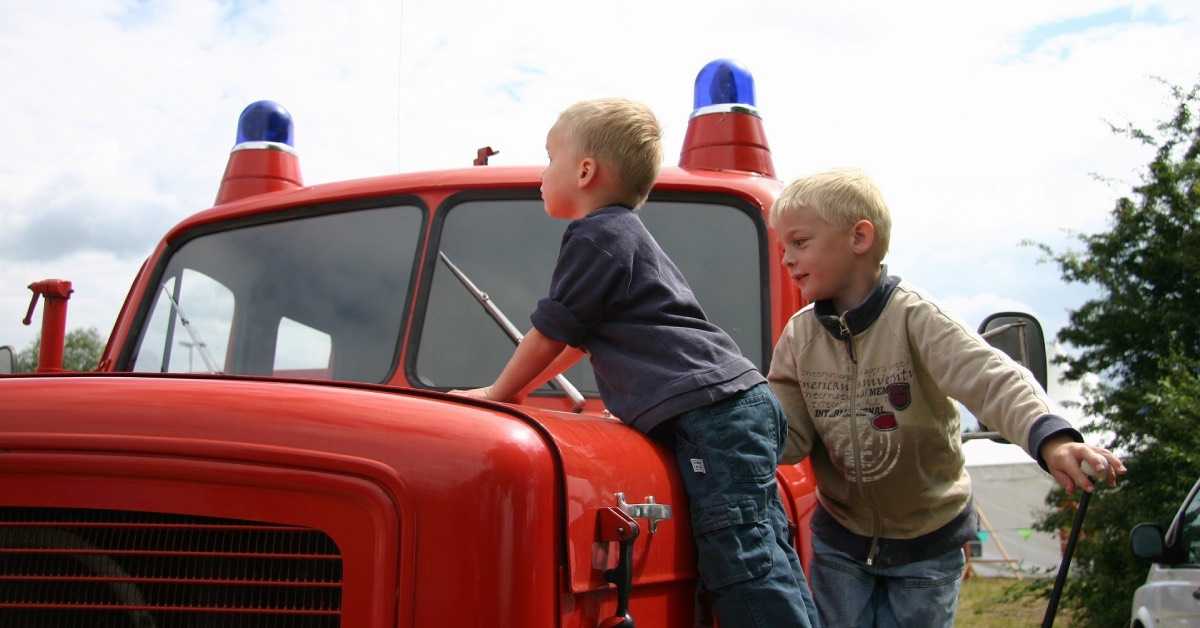 Zwei Jungen klettern beim Feuerwehr Geburtstag auf ein altes Feuerwehrfahrzeug