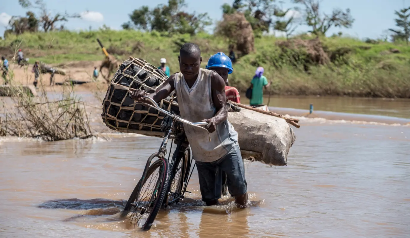 Zaccharia Roberto pushes his bicycle laden with charcoal across a flooded river near Nhamatanda, Mozambique.