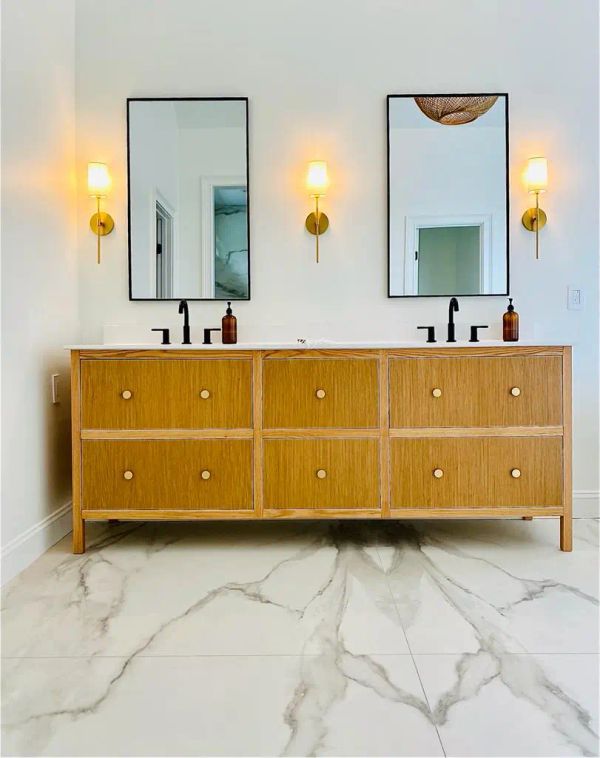 Remodeled Bathroom with golden light fixtures and a light wood finish on the cabinet