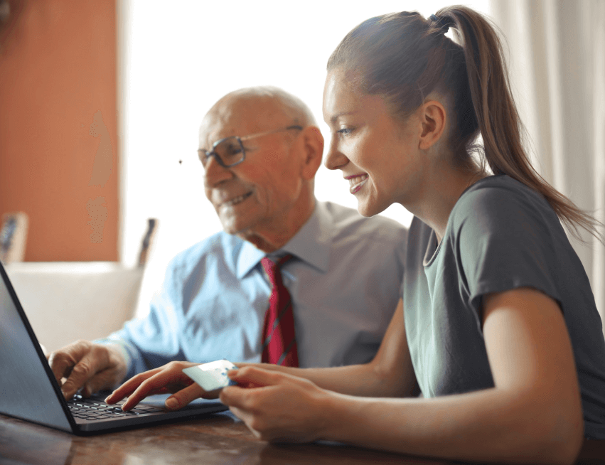 Young woman helping senior man with payment on Internet using laptop