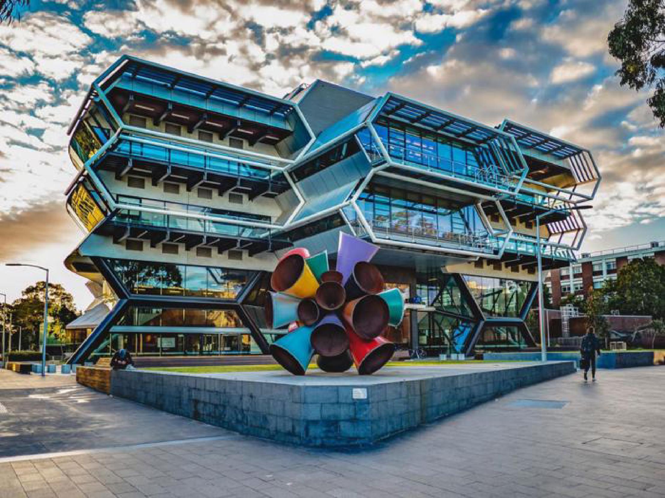 Thumbnail A colorful metal sculpture in fron of a modern building with 2 hexagonal floors