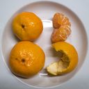 Mandarins on a small plate. Two touch to make an eight, a split and peeled third makes the digit three.