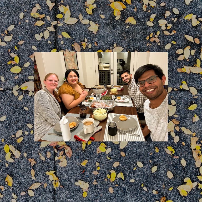 Two women and two men gathered around a table full of serving dishes ready to portion out. This photo is superimposed on top of a textural photo of small leaves scattered on a sidewalk.