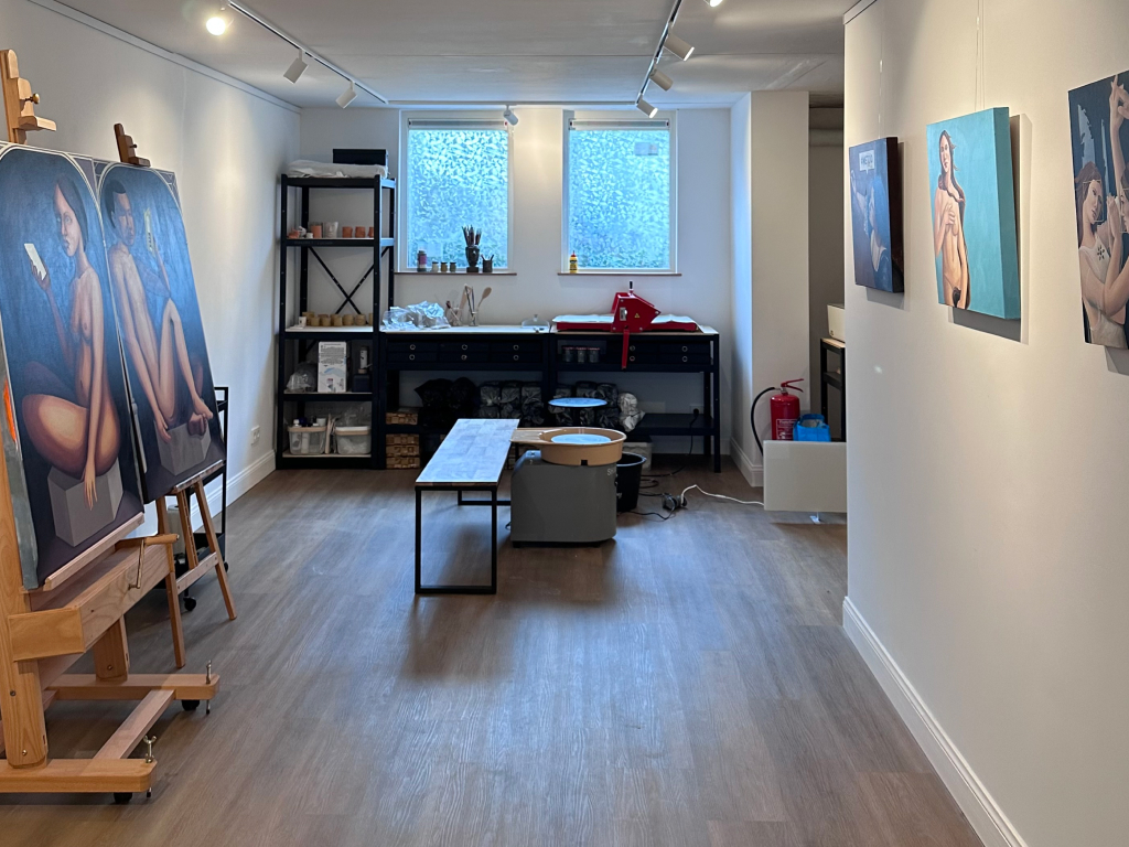 An image of an art studio with paintings and a ceramics wheel