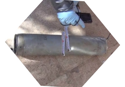 Photo shows the gloved hand of a UN / OPCW inspector taking a picture of the measurements of a M-14-S artillery rocket motor recovered after a chemical attack in Mu'addamiyat ash Shaykh, West Damascus on 21 August 2013. There is a factory marking on the casing which reads “179”, which indicates that the munition is a Soviet production. The rocket is lying on the ground. The photo appeared in Brown Moses blog in 2013.