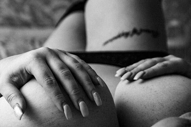 A woman lying in bed cupping her breasts.