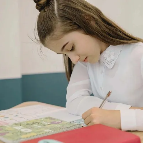 A learner reading and writing in a classroom