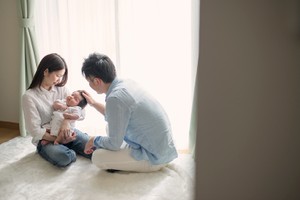 Asian parents having a good time with cute baby girl on holiday at home