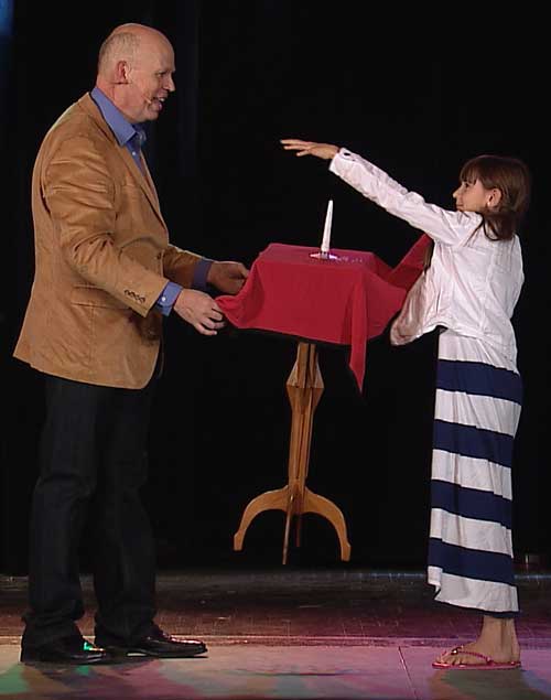 A child helps Brad make a table float on stage